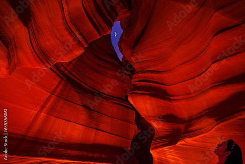 Navajo girl staring at moon through slot at Antelope Canyon at night