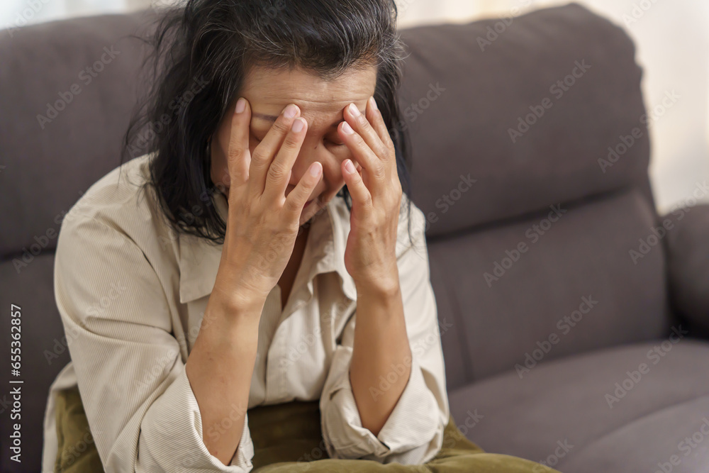Sad middle age Asian woman touching forehead having headache suffering from migraine. mature asian woman feeling sick or depression. Sad middle age Asian woman touching forehead having headache suffering from migraine. mature asian woman feeling sick or depression.