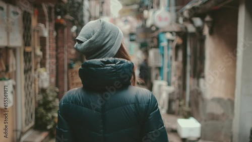 Tourist girl explore Japanese culture walking Golden Gai Tokyo streets. Woman back view enjoy backstreet alley, bars, shops. Outdoor lifestyle travel on autumn holiday vacation. Slow motion 4K