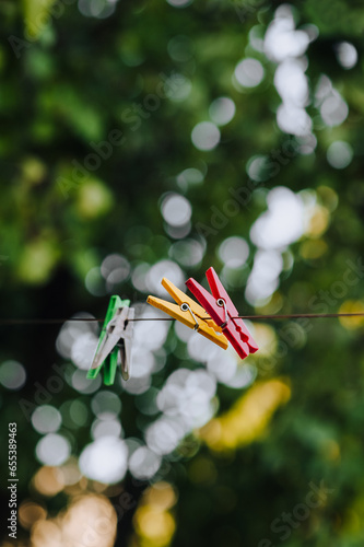 Colored plastic clothespins hanging on a rope outdoors. Photography, housework.
