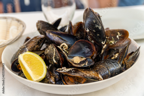  Steamed mussels with lemon, served on a white plate.