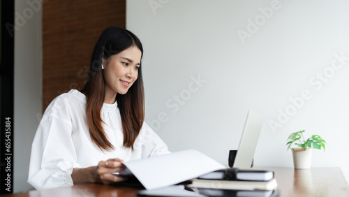 Writer woman reading to checking document and typing business information content on laptop in cafe photo