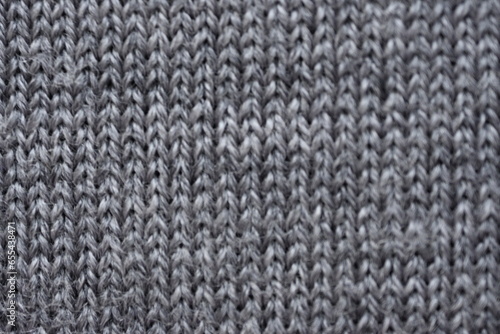 macro texture of gray woolen sweater, close up of a piece of knitted fabric, winter woolen piece of crocheted fabric as a background 