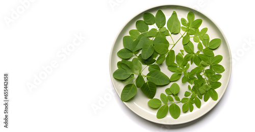 Plate with leaves of moringa plant on white background photo