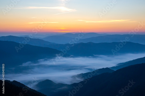 Morning dense fog in the mountainous forest area of       the Ukrainian Carpathians. Landscape in nature. Dawn in the mountains