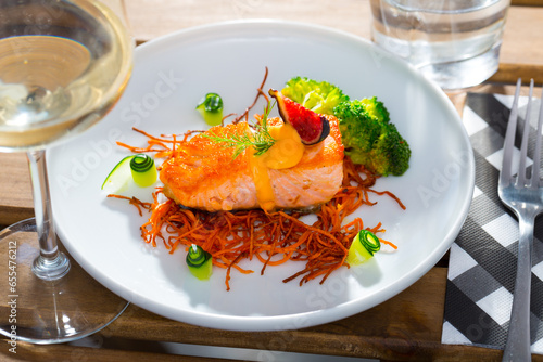 Delicious roasted salmon on pillow of smoked carrots served with fresh vegetables on plate