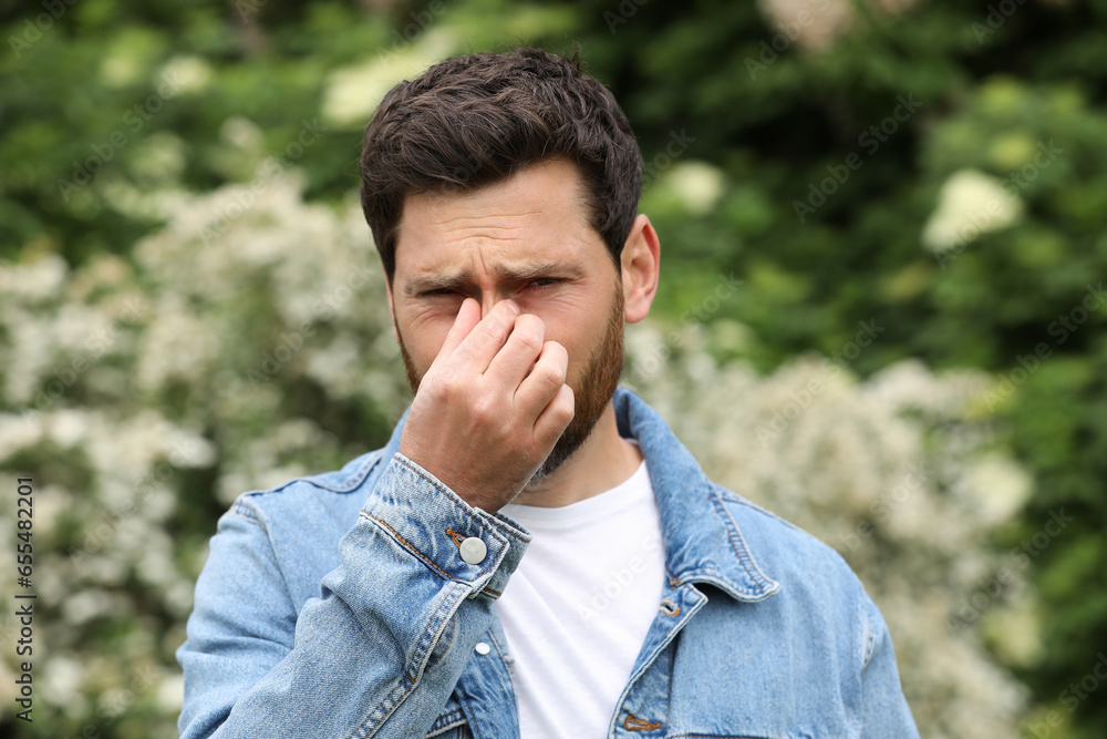 Man suffering from seasonal spring allergy outdoors
