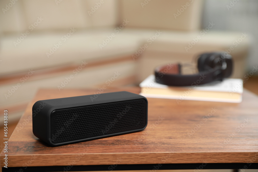 One black portable bluetooth speaker on wooden table indoors, space for text. Audio equipment One black portable bluetooth speaker on wooden table indoors, space for text. Audio equipment