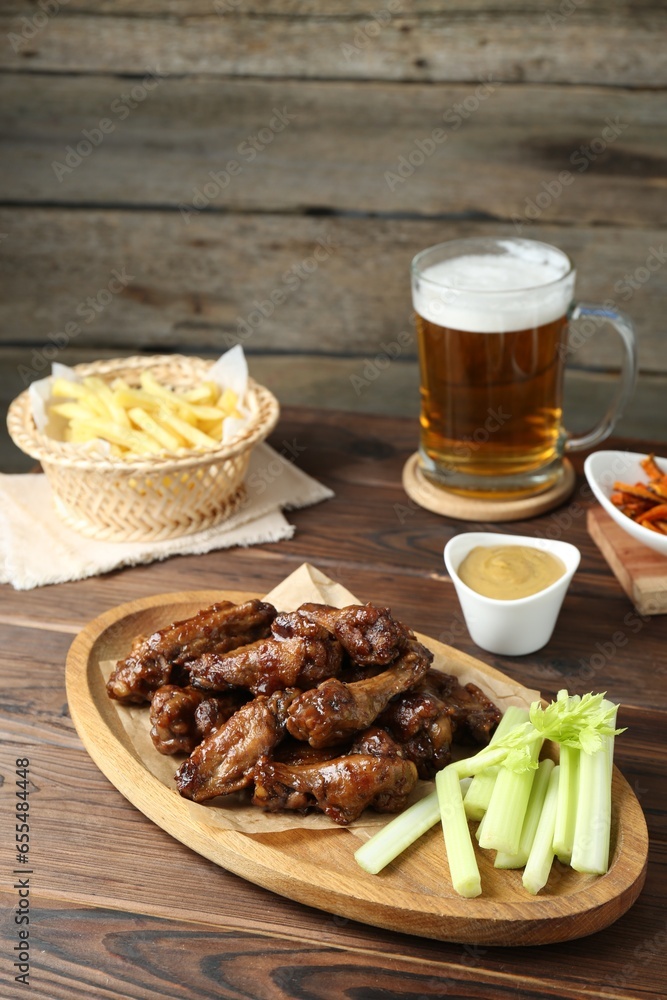 Delicious chicken wings served with beer on wooden table