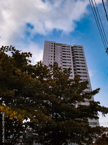 Building with tree and clouds in the city, building seen from below, photo of building at dawn, photo taken in Brazil