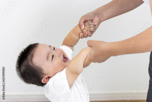母親と手をつないでつかまり立ちする赤ちゃん（男の子、生後9カ月、1歳、日本人）