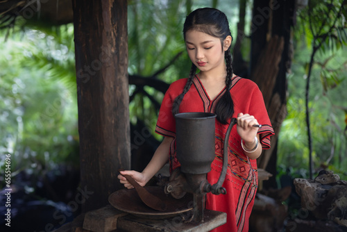 Asian traveler girls in Karen women dress in traditional clothing. Grinding coffee beans using the ancient method at Doi Inthanon National Park a tourist attraction Chiang Mai Northern, Thailand.