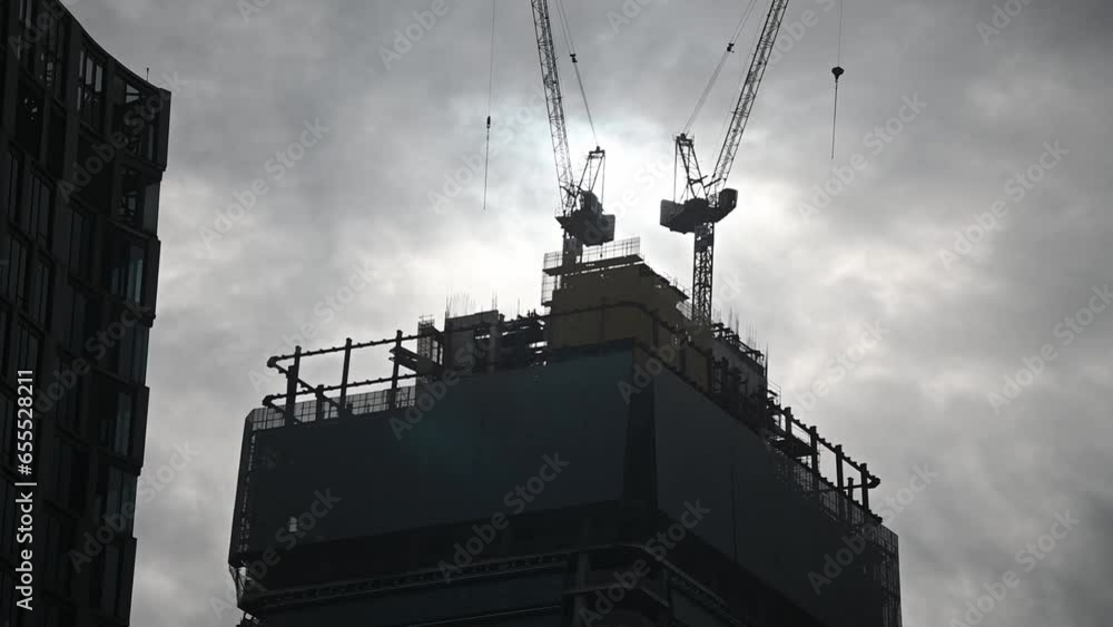 Tower crane on a construction site lifts a load at a high-rise building ...
