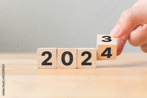 New year 2023 change to 2024. Hand flip over wooden cube block. New year resolution goal concept