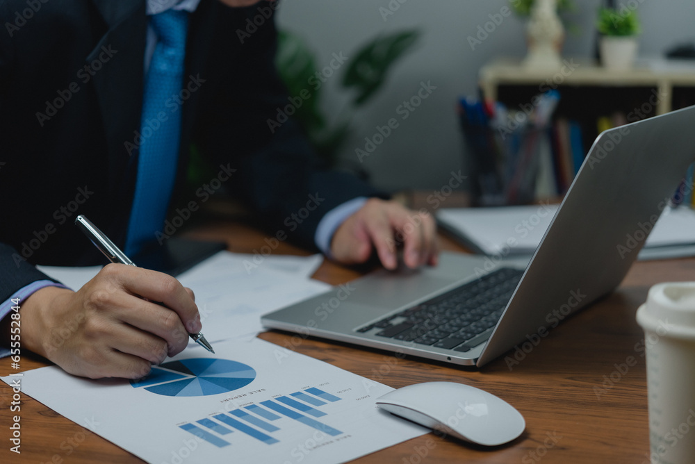 Businessman pointing chart analysis document and paperwork financial plan marketing with laptop on desk office. Businessman pointing chart analysis document and paperwork financial plan marketing with laptop on desk office.