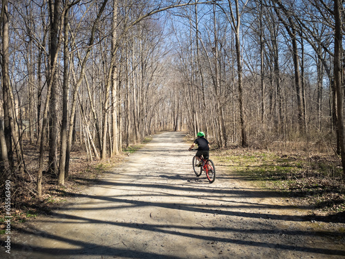 Young boy riding bicycle on path in early spring.