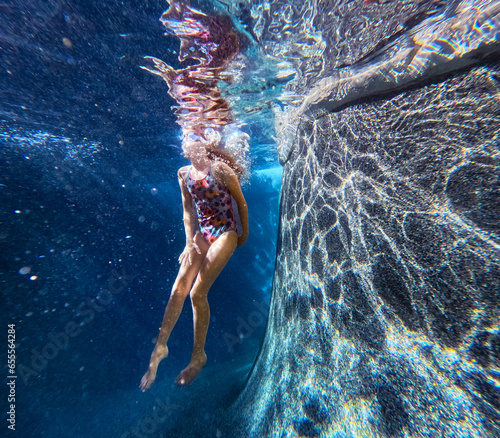 Canvas Print Girl swimming with goggles in swim pool with bokeh underwater