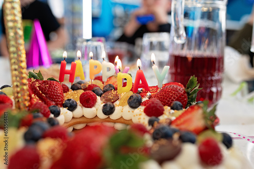 Birthday cake with candles and berries on a table in a restaurant