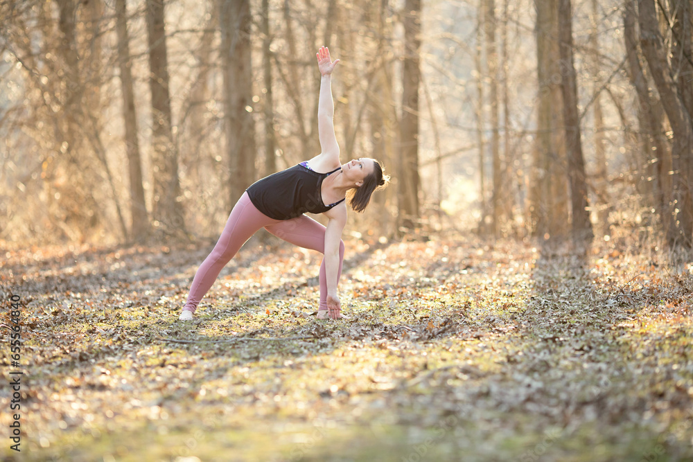 Fototapeta premium Triangle yoga pose; woman practicing yoga outside