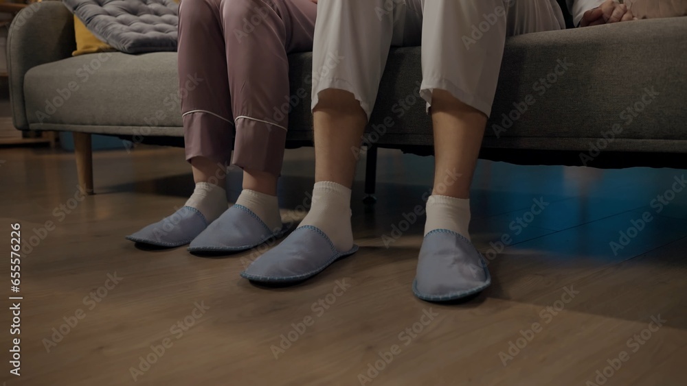 Portrait of young couple spending time together. Closeup shot of man and woman sitting on the sofa in pajamas and slippers.
