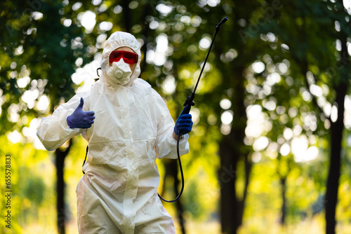 A worker in special clothing for working with pesticides in an outdoor park. Pest control, insect disinfestation