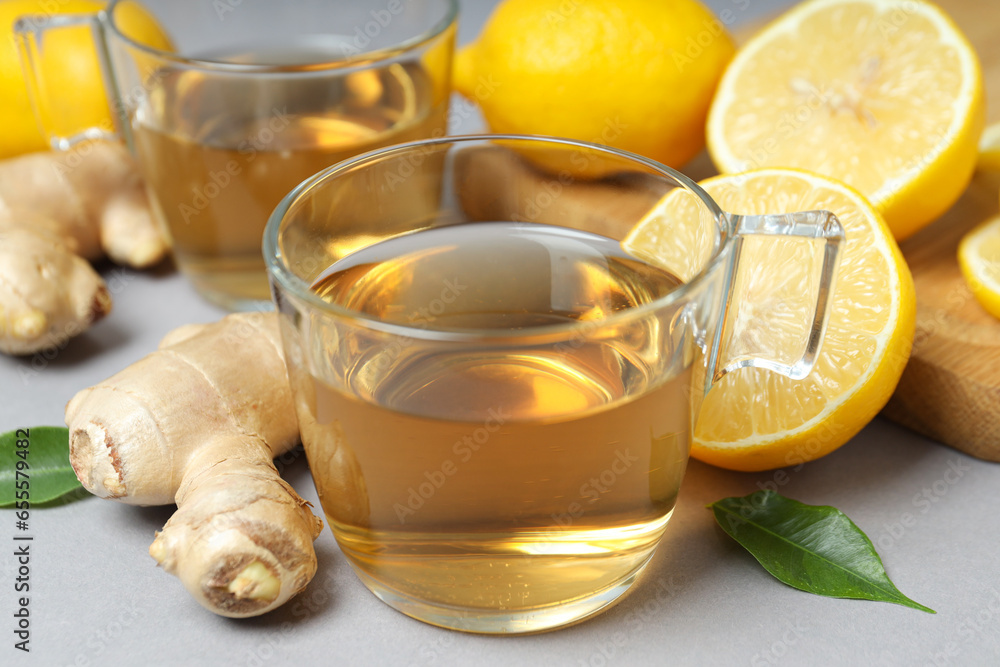 Cups of tea, ginger and lemons on gray background, close up Cups of tea, ginger and lemons on gray background, close up