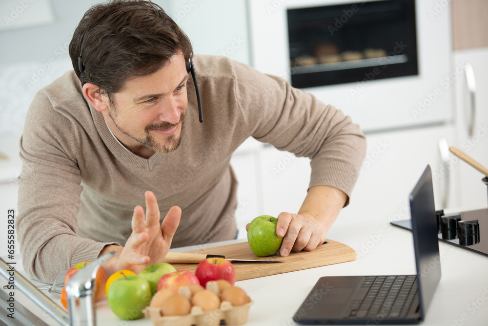 man preparing fruit while waving to laptop screen man preparing fruit while waving to laptop screen