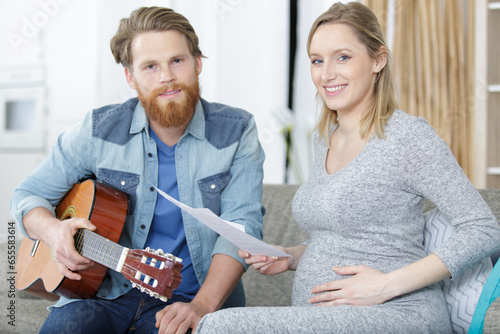 pregnant woman and husband are playing acoustic guitar