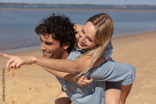 guy carrying a girl on his back at the beach