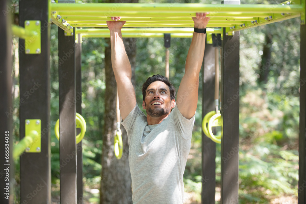 Obraz premium athletic brunette man pressed on parallel bars at street gym