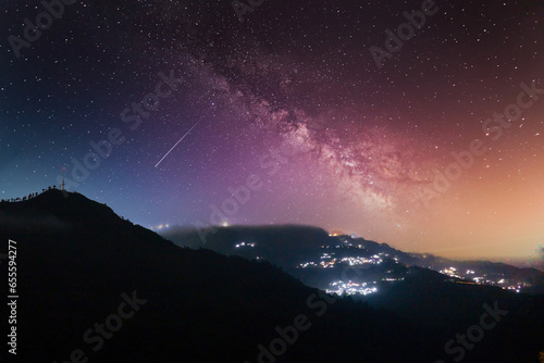 Night long exposure shot showing fog rolling over hills with village in distance showing prestine hills of darjeeling, shimla, manali, landsdowne photo