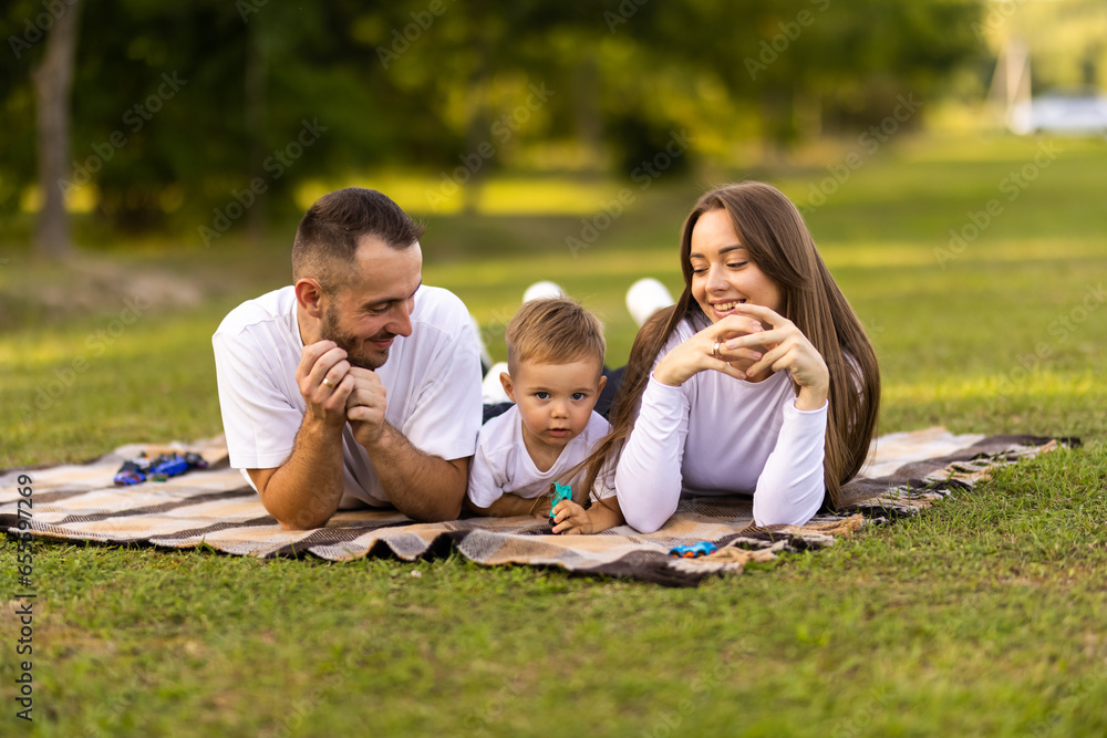 Happy family with little son on summer picnic in park