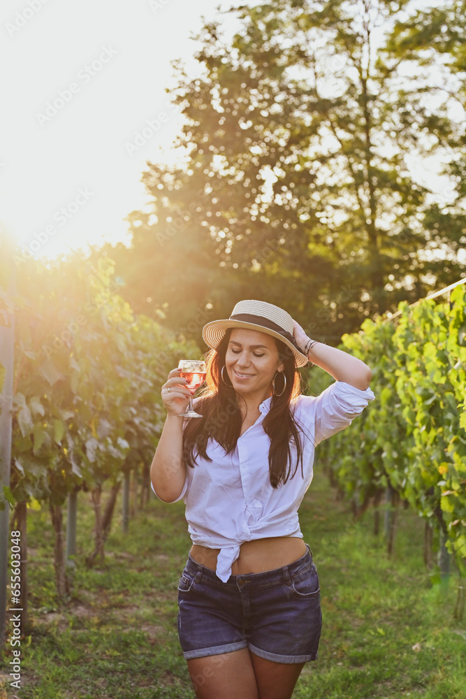 Young beautiful Smiling  italian woman walking at wineyard with a Glass of Red wine.Wine tourism at Tuscany,Italy