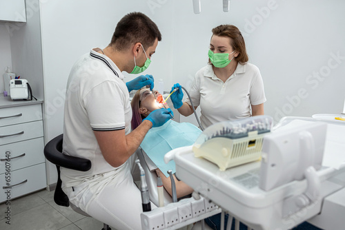 male dentist and a female assistant treat a patient.