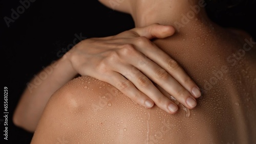 Closeup studio shot of beautiful woman body  touching skin with water drops on the shoulder back area after bathing.