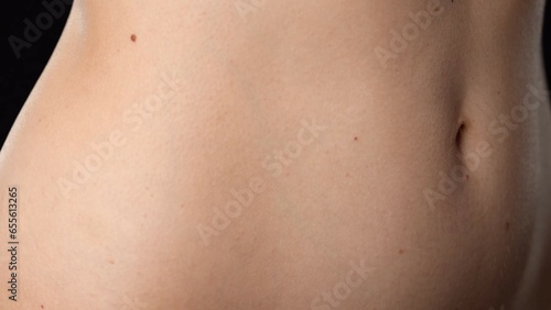 Closeup studio shot of beautiful caucasian woman model body part, tummy waist area smooth skin with belly button,