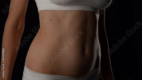 Closeup studio shot of beautiful caucasian woman body part, waist and tummy area, wearing white underwear.