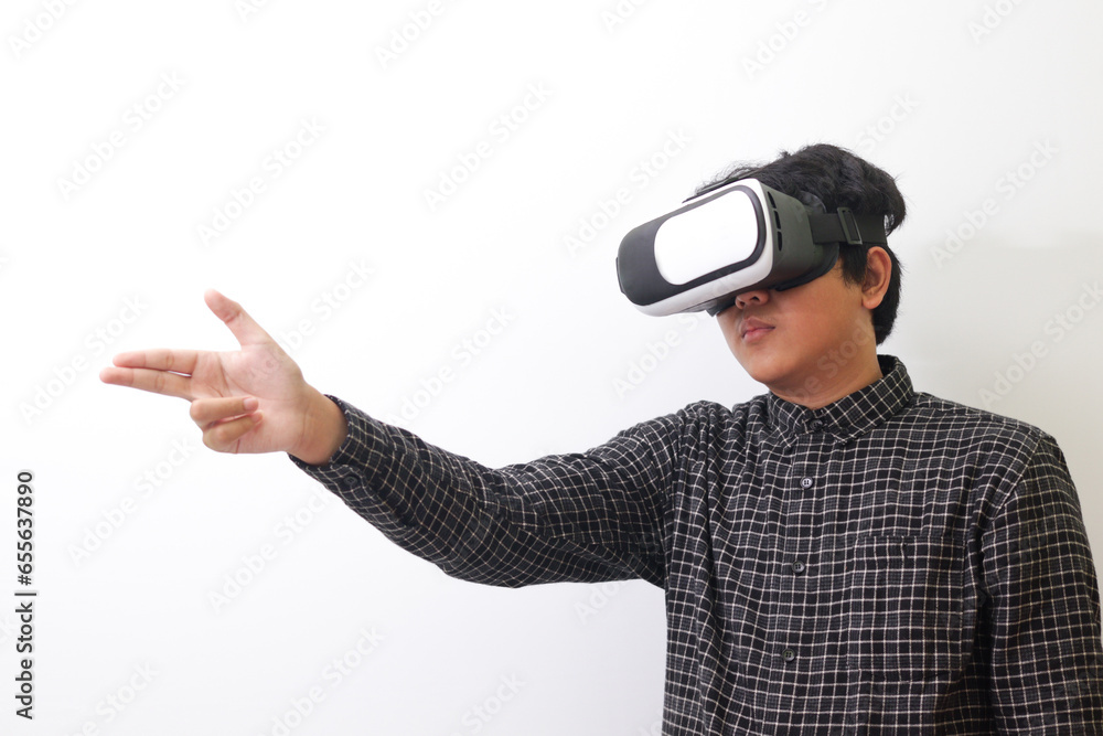 Portrait of Asian man in black plaid shirt using Virtual Reality (VR) glasses and greet his friend inside the game with opened palm. Isolated image on white background Portrait of Asian man in black plaid shirt using Virtual Reality (VR) glasses and greet his friend inside the game with opened palm. Isolated image on white background