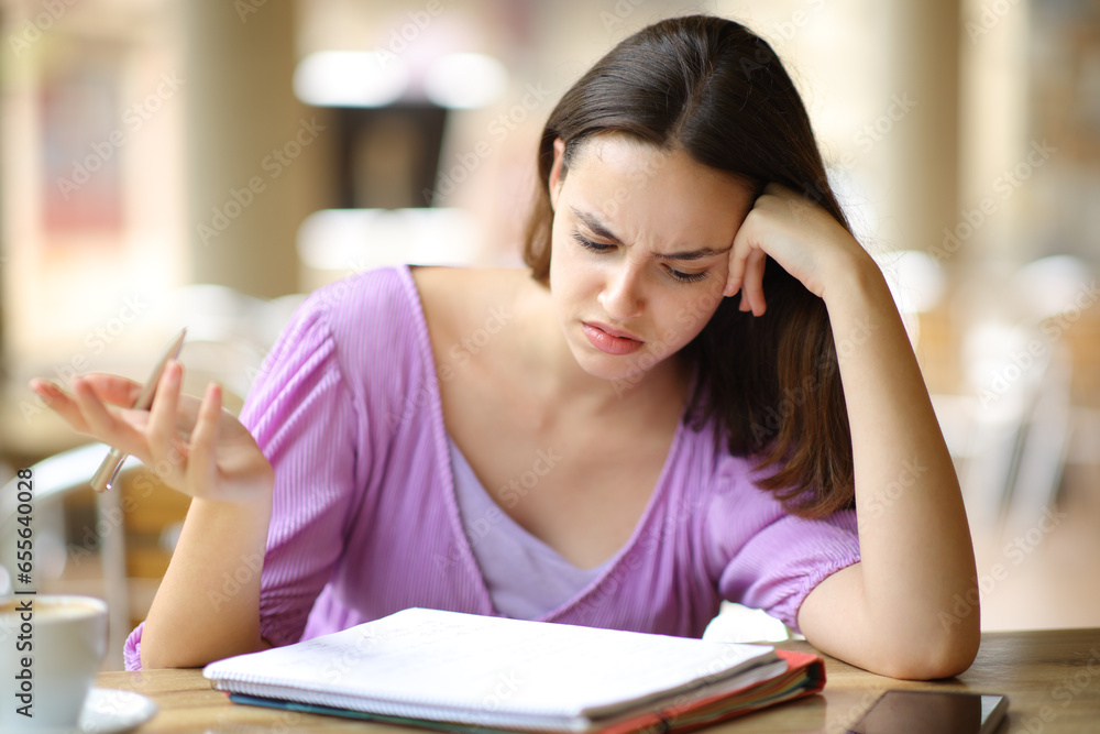 Confused student checking lesson in a bar Confused student checking lesson in a bar