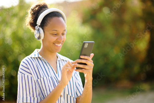 Happy black woman listening audio with headphone and phone
