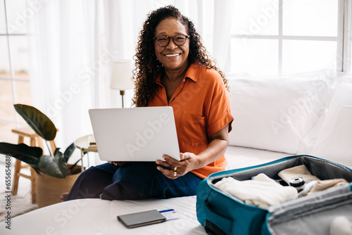 Картината върху платно Happy woman making travel bookings using a laptop, preparing for a solo vacation