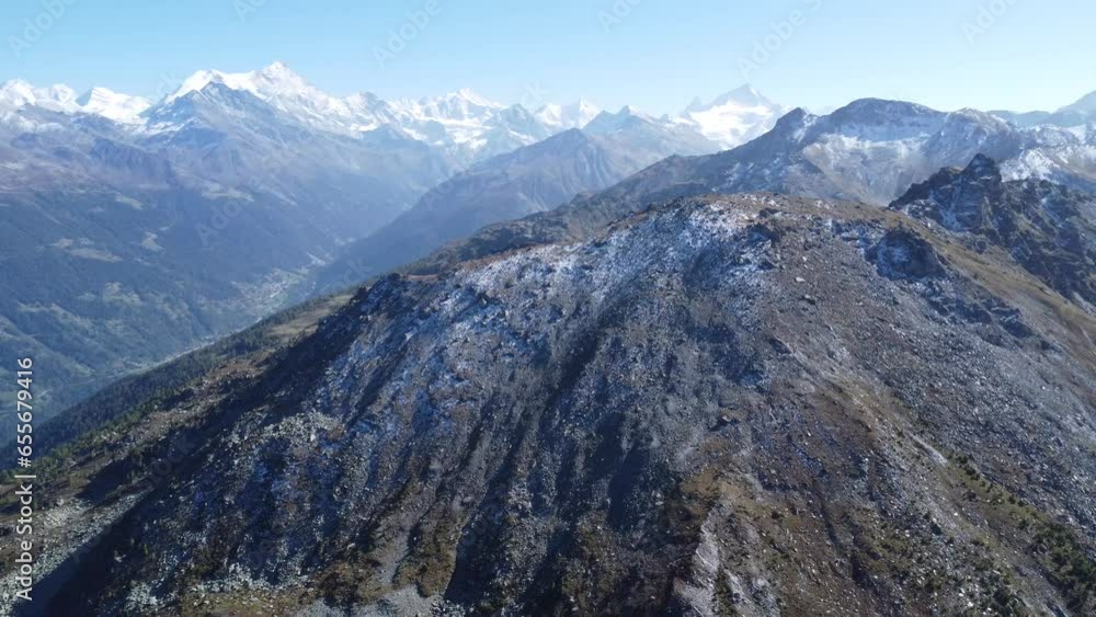 a big rock in front of snowy mountains ins the swiss alps, aerial drone
