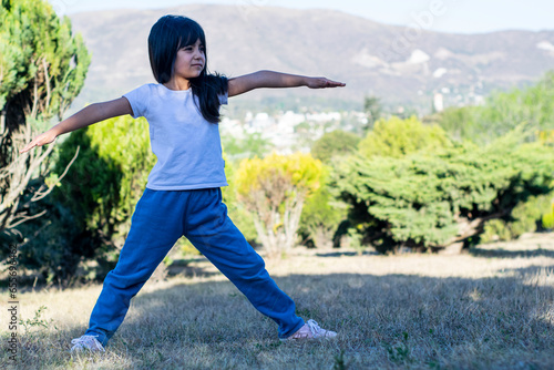 Fotografie Niña haciendo ejercicios en un hermoso parque con colores verdes brillantes y montañas al fondo