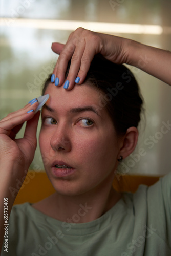 Woman is massaging her face scraper gua sha.