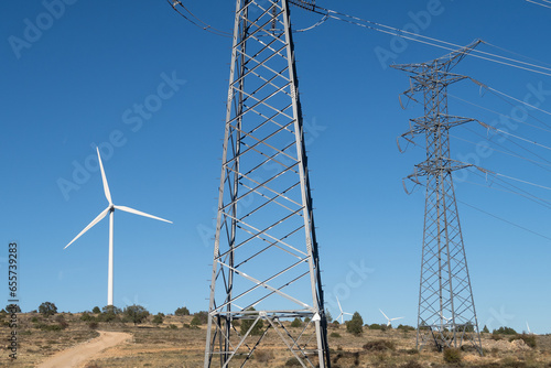 Vista de una linea electrica de alta tensión y un aerogenerador en un parque eolico.