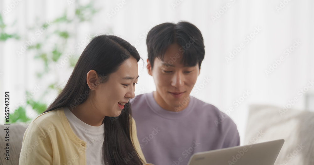 Portrait of a Happy South Korean Couple Spending Quality Time at Home, Creating a Harmonious Atmosphere in Their Cozy Apartment, Streaming and Enjoying a K-Drama TV Show on a Laptop Computer Portrait of a Happy South Korean Couple Spending Quality Time at Home, Creating a Harmonious Atmosphere in Their Cozy Apartment, Streaming and Enjoying a K-Drama TV Show on a Laptop Computer