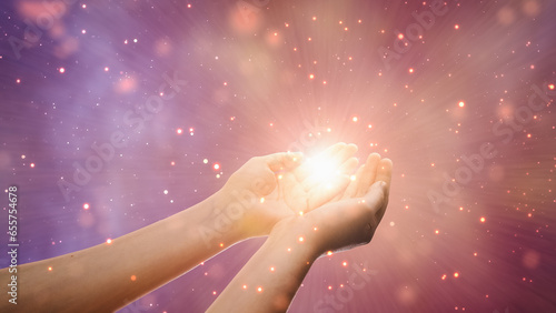 Conceptual Visualization Of Male Or Female Hands Reaching Out In Prayer On Magical Dark Purple Background. Person Connecting With Higher Spiritual Energy Through Bright Light In Their Palms. photo