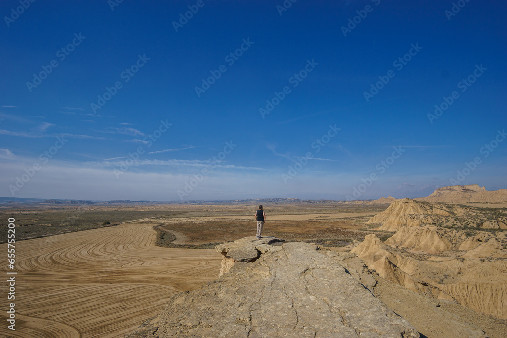Hiker at Mirador de Juan Obispo looking at desert landscape of the arid plateau of the Bardenas Reales, Arguedas, Navarra, Spain