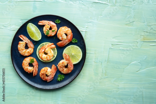 Shrimps, shot from above with a place for text on a teal blue table. Cooked shrimp with lime, tasty gourmet dish