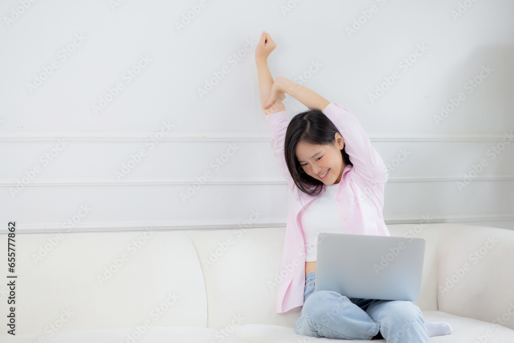 Beautiful young asian businesswoman sitting on sofa and working from home and break while stretch arm for relax in living room at home, woman is freelance working on laptop computer, business concept. Beautiful young asian businesswoman sitting on sofa and working from home and break while stretch arm for relax in living room at home, woman is freelance working on laptop computer, business concept.